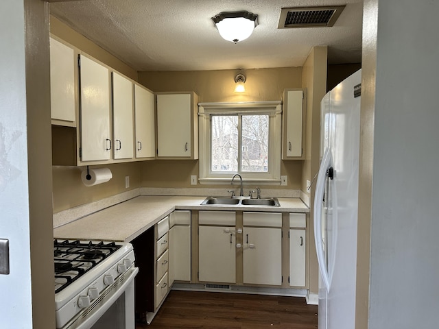 kitchen featuring white appliances, visible vents, light countertops, and a sink