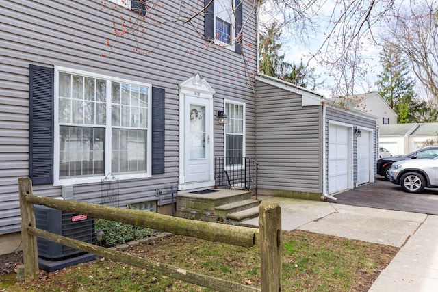 doorway to property featuring a garage and cooling unit