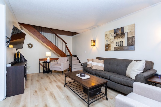 living area featuring stairway, light wood-style floors, and ornamental molding