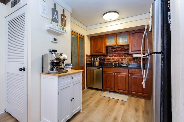 kitchen featuring a sink, appliances with stainless steel finishes, dark countertops, and light wood finished floors