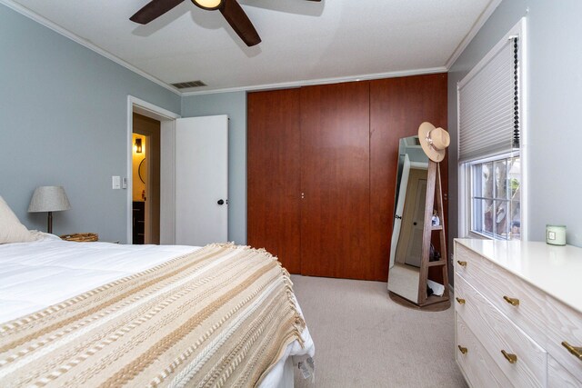 bedroom featuring light carpet, a closet, crown molding, and visible vents