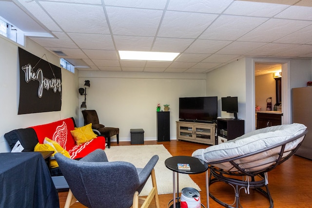 living room featuring visible vents, baseboards, a drop ceiling, and wood finished floors