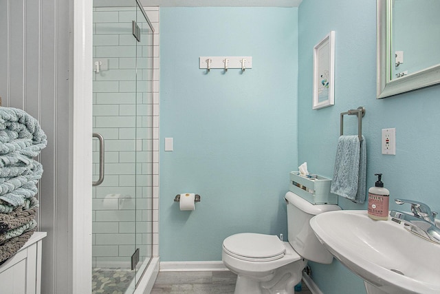 full bathroom featuring a stall shower, toilet, a sink, wood finished floors, and baseboards
