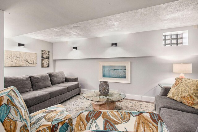 living area featuring wood finished floors, baseboards, and a textured ceiling