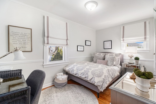 bedroom with ornamental molding and wood finished floors