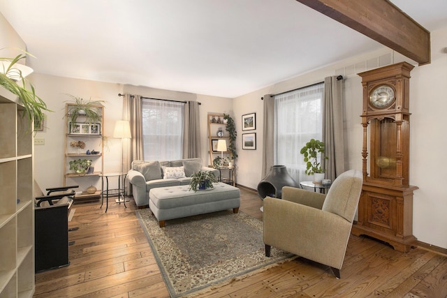 living area featuring baseboards, beam ceiling, hardwood / wood-style flooring, and a healthy amount of sunlight