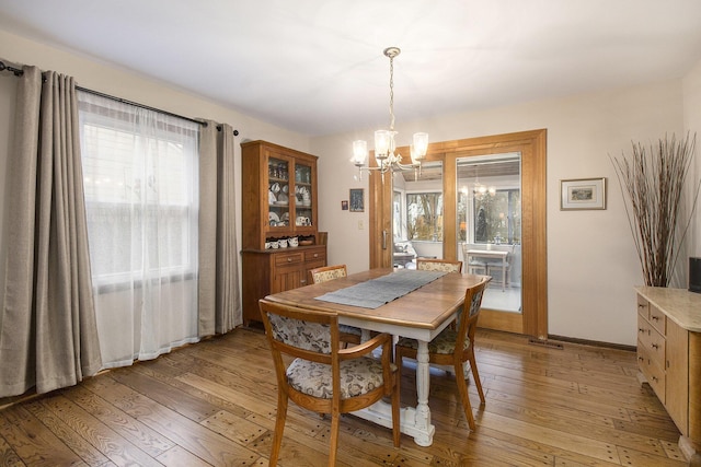 dining area with plenty of natural light, a notable chandelier, and light wood-style floors