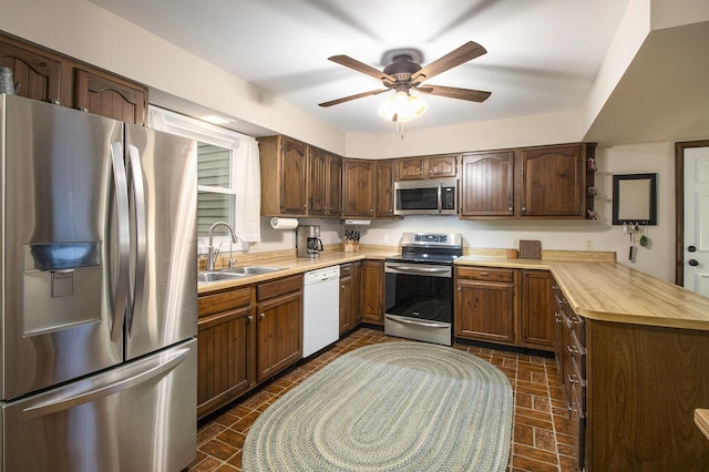 kitchen with a sink, light countertops, appliances with stainless steel finishes, and a peninsula