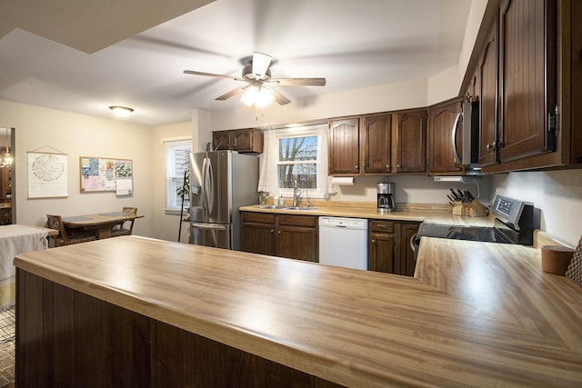 kitchen featuring dark brown cabinetry, a sink, appliances with stainless steel finishes, wooden counters, and ceiling fan