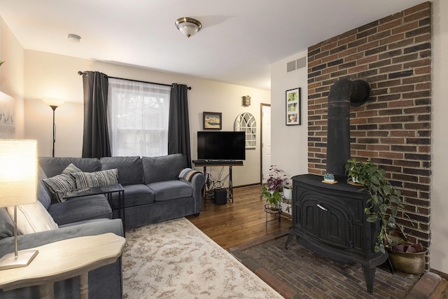 living room featuring visible vents, a wood stove, and wood finished floors