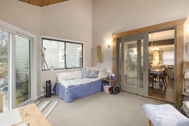 carpeted bedroom with a towering ceiling, multiple windows, and a chandelier