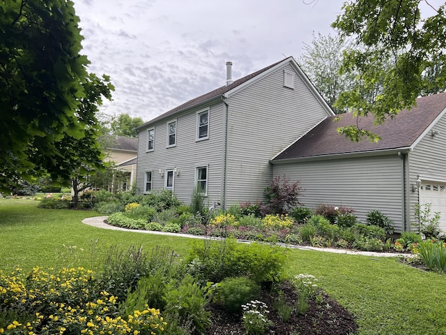 exterior space featuring roof with shingles, a garage, and a yard