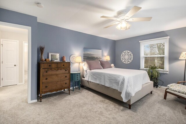 bedroom with a ceiling fan, light carpet, and baseboards