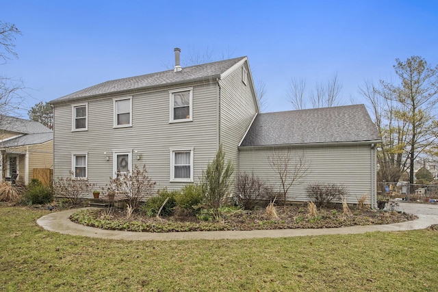 back of property with a shingled roof and a yard