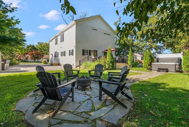 exterior space featuring a fire pit, a lawn, a hot tub, and a patio area