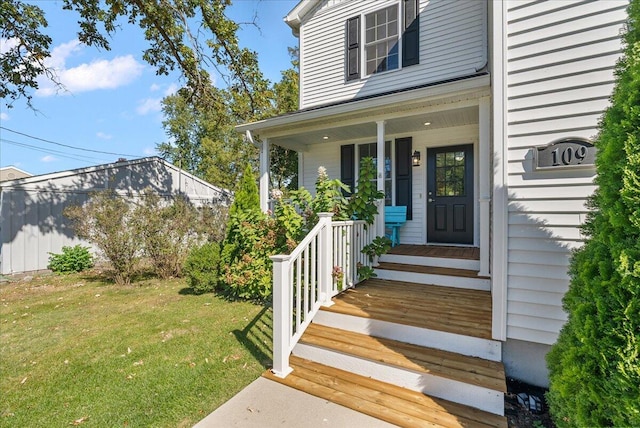 view of exterior entry with covered porch and a yard