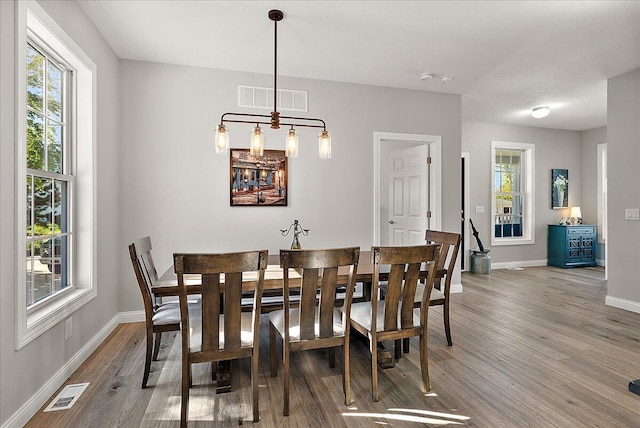 dining room featuring baseboards, visible vents, and wood finished floors