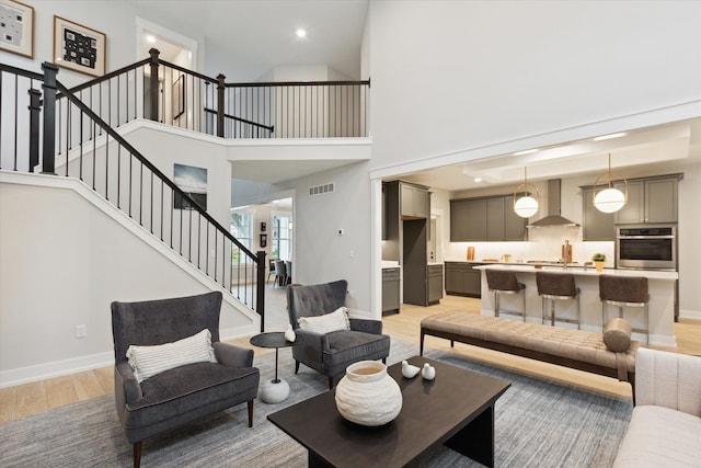 50272 Hedgewood Dr, Canton, MI 48187 - living room with stairs, baseboards, a towering ceiling, light wood-style floors, and visible vents