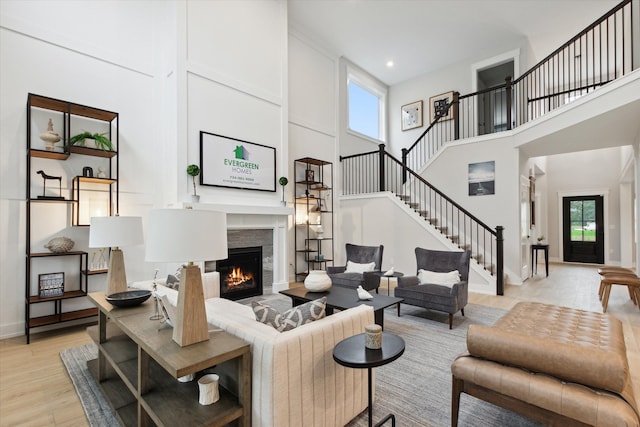 50272 Hedgewood Dr, Canton, MI 48187 - living room with stairway, baseboards, a lit fireplace, a high ceiling, and light wood-style flooring