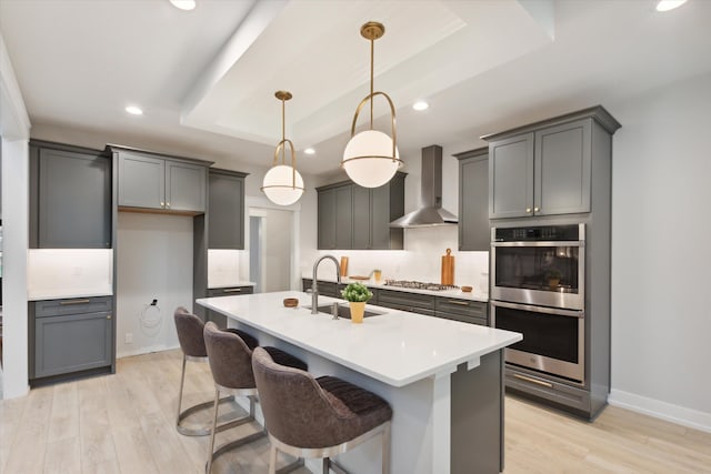 50272 Hedgewood Dr, Canton, MI 48187 - kitchen with a tray ceiling, a sink, light wood finished floors, wall chimney exhaust hood, and stainless steel appliances