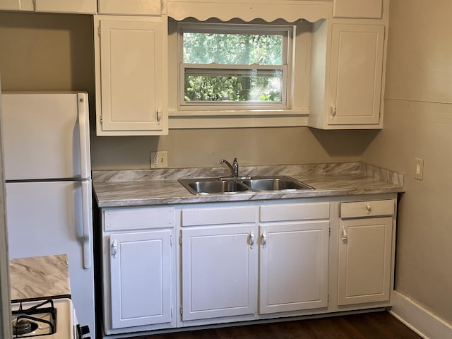kitchen featuring white cabinets, light countertops, a sink, and freestanding refrigerator