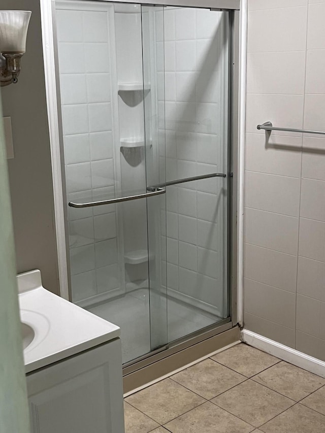 full bathroom featuring a stall shower, vanity, and tile patterned flooring
