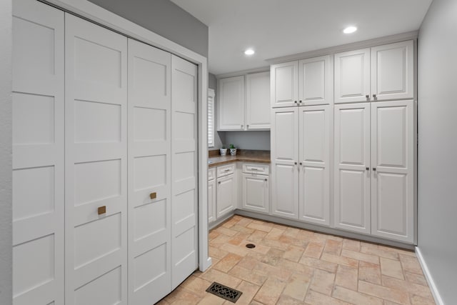 kitchen featuring recessed lighting, white cabinetry, brick floor, and dark countertops