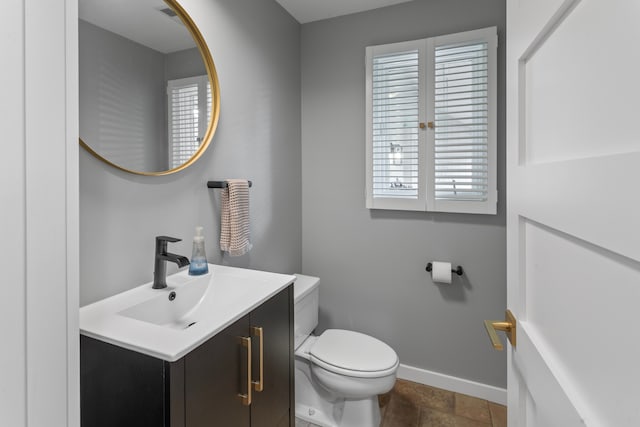 bathroom featuring baseboards, toilet, and vanity