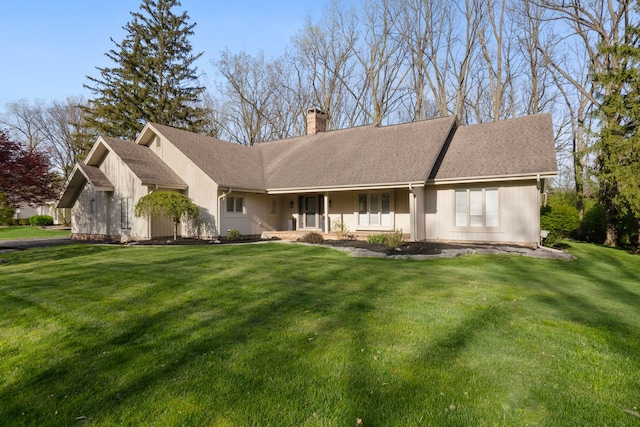 rear view of property with covered porch, a chimney, and a yard