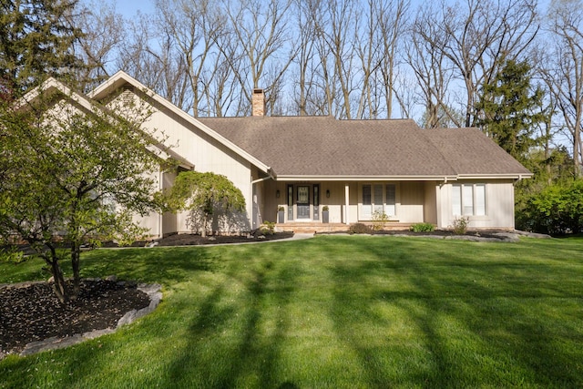 view of front facade with a porch, a chimney, a shingled roof, and a front lawn