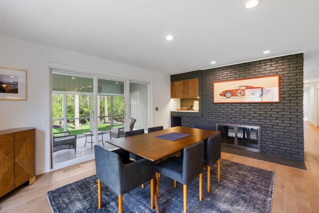 dining area featuring a brick fireplace, recessed lighting, visible vents, and light wood-style flooring