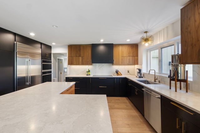 kitchen featuring a sink, light wood-style floors, light countertops, stainless steel appliances, and range hood