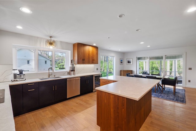 kitchen featuring light countertops, beverage cooler, a sink, and dishwasher