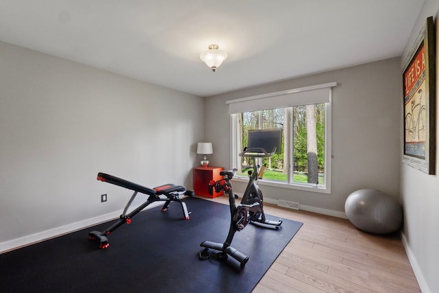 workout room featuring baseboards, wood finished floors, and visible vents