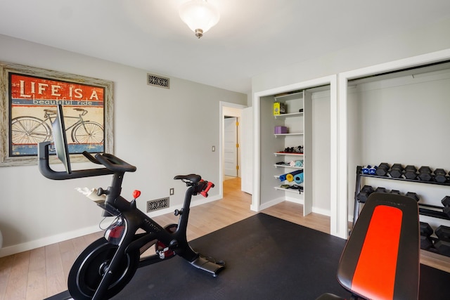 workout area featuring baseboards, wood finished floors, and visible vents