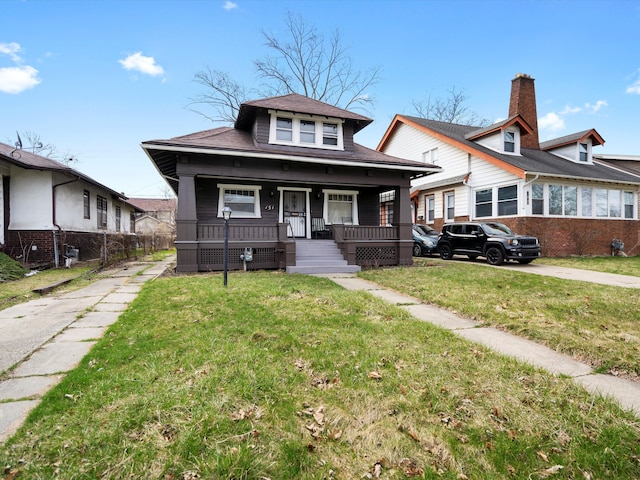 bungalow-style house featuring a porch, roof with shingles, and a front lawn