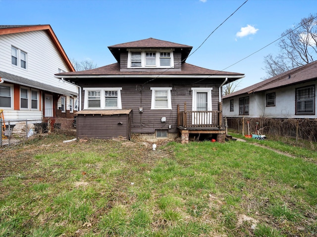 rear view of property featuring a yard, fence, and roof with shingles