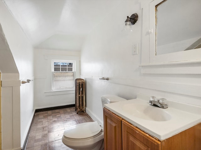 bathroom featuring baseboards, toilet, radiator, vanity, and vaulted ceiling