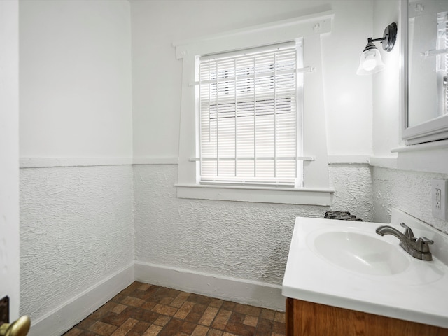 bathroom with vanity, brick floor, and baseboards