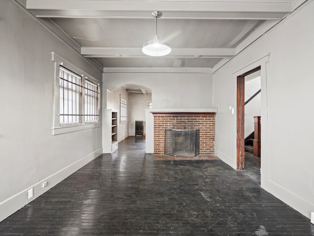 unfurnished living room featuring beamed ceiling, a fireplace, arched walkways, wood finished floors, and stairs