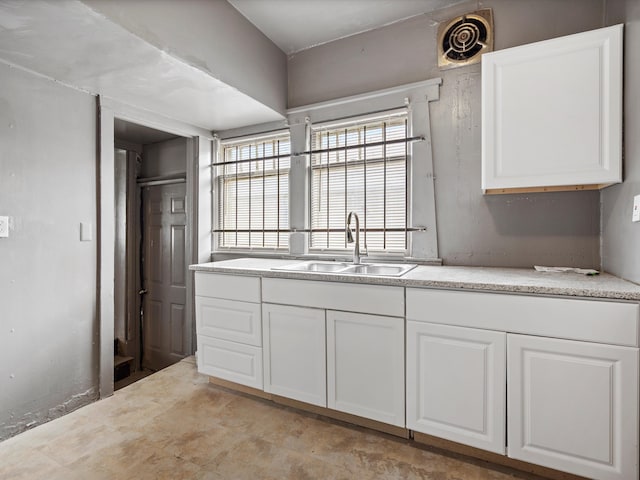 kitchen with white cabinets, a sink, light countertops, and visible vents
