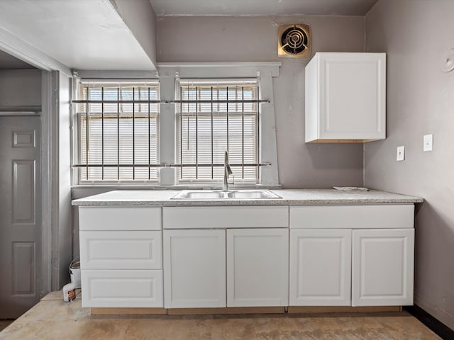 kitchen with light countertops, visible vents, white cabinetry, and a sink