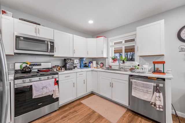 kitchen with white cabinets, stainless steel appliances, light countertops, and light wood-style flooring