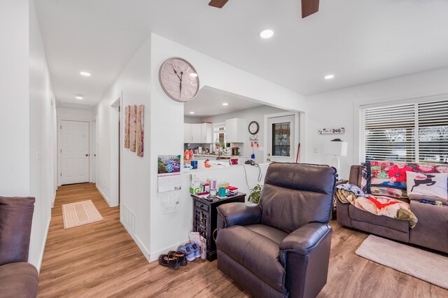 living room featuring light wood finished floors, plenty of natural light, a ceiling fan, and baseboards