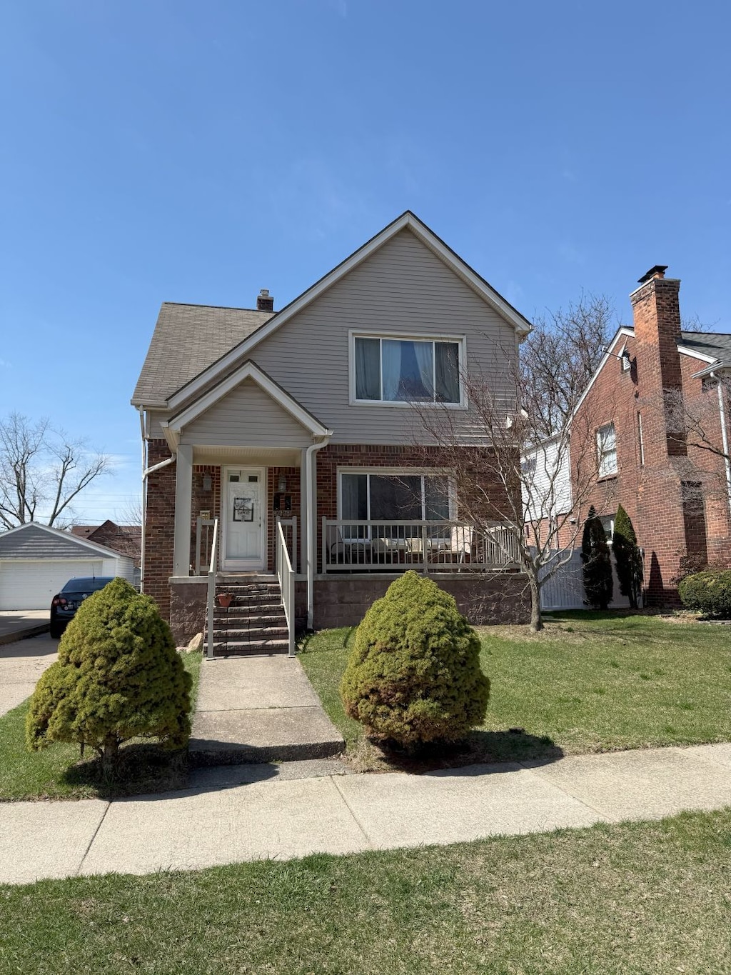 view of front of home featuring brick siding, a porch, a garage, and a front lawn