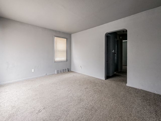 16665 San Juan Dr, Detroit, MI 48221 - empty room with arched walkways, visible vents, and carpet floors