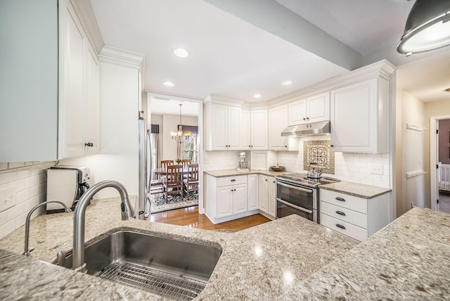 kitchen featuring a notable chandelier, a sink, under cabinet range hood, white cabinetry, and range with two ovens