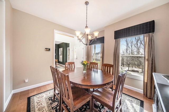 dining area featuring a chandelier, light wood-type flooring, and baseboards