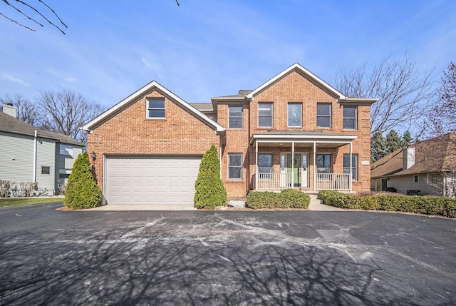 view of front of property with aphalt driveway, brick siding, and covered porch