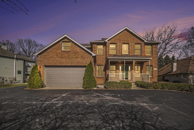 traditional-style home with aphalt driveway, brick siding, and covered porch